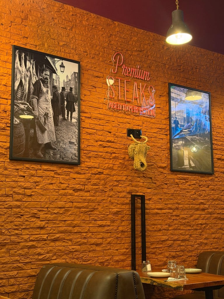 La salle : mur de brique, néon « Premium Steaks » et banquettes